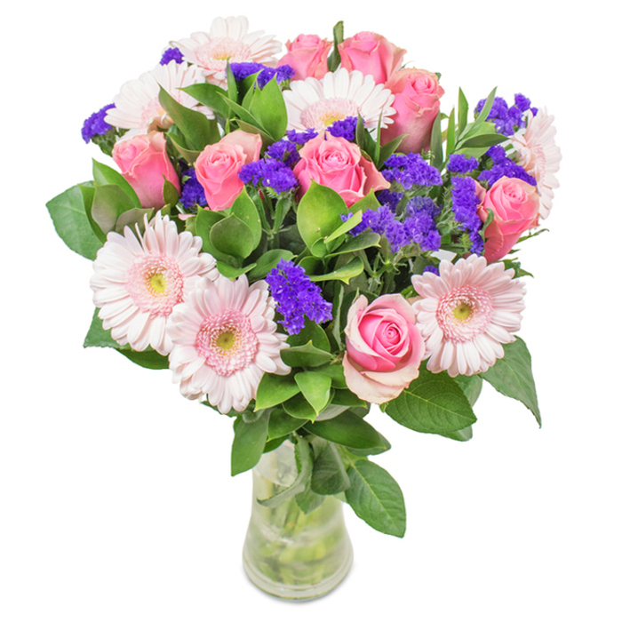 Set against a pristine white backdrop, this meticulously arranged floral bouquet from a professional Epsom florist brings together approximately seven to nine medium and softly blushed pink roses, many with petals that remain gently furled or just beginning to reveal their iconic spirals. The roses' classical elegance is beautifully accompanied by five to seven pale pink gerbera daisies whose expansive, rounded faces and delicate, nearly white centers radiate sophistication. Threaded throughout are vivid purple clusters of what appear to be statice or limonium, providing energetic pops of colour and a layered, tactile contrast. The assembly is grounded in a generous base of deep green foliage, evoking the lushness of the town's green spaces and enhancing both the freshness and vitality of the arrangement. Their clear glass vase, water shimmering around the visible stems, conveys both purity and an authentic sense of just-delivered freshness. Suitable for commemorating birthdays, anniversaries, or Mother's Day-or as a serene embellishment for a welcoming Epsom home or office-this arrangement of pink roses, daisies, and purple accents expresses joy, celebration, and heartfelt affection, drawing on the refined florist tradition cherished in Epsom.